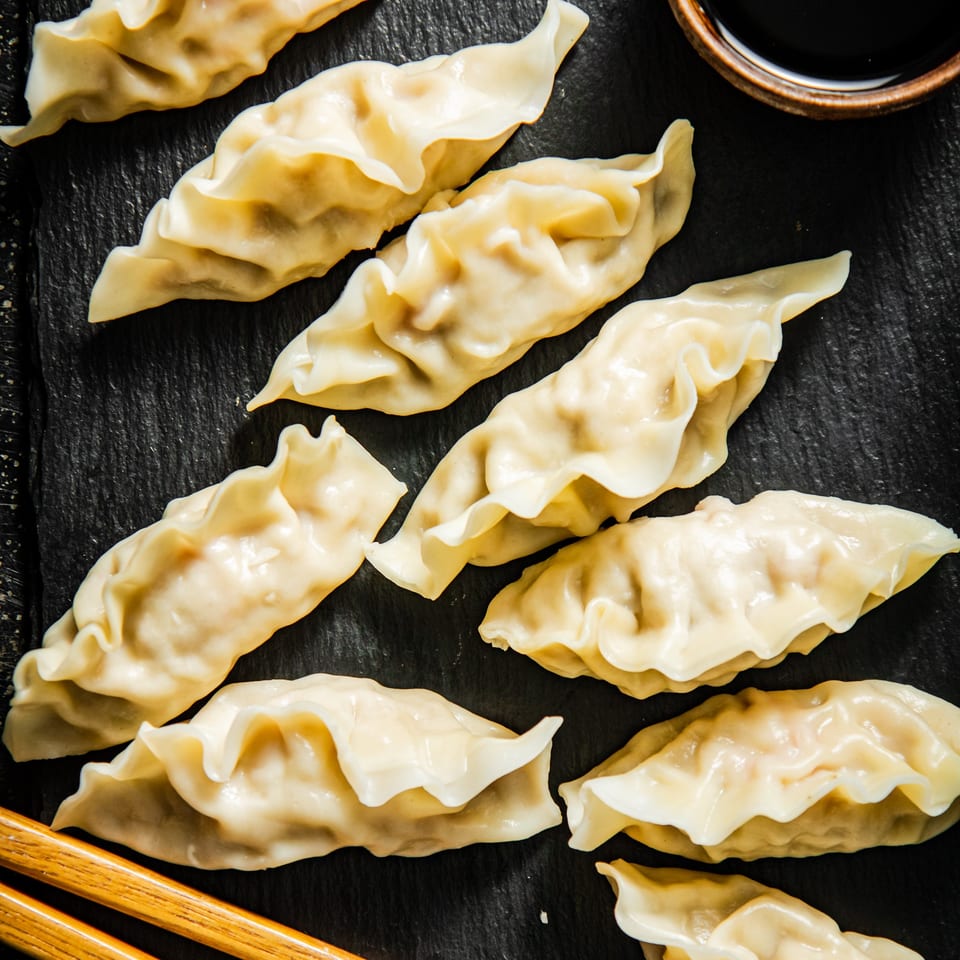 Steamed Vietnamese dumplings arranged on a dark slate, with chopsticks and a small bowl of sauce.